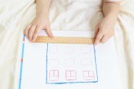 Child designing and measuring a house